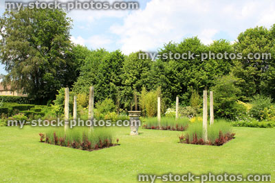 Stock image of formal garden, green lawn with flower borders, berberis, stone columns