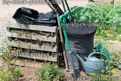 Stock image of allotment vegetable garden, pallet wood compost heap, watering can, spades