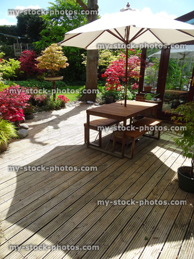 Stock image of garden timber decking, table and benches with parasol umbrella