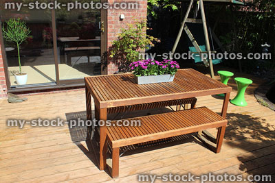 Stock image of slatted wooden table and benches, garden furniture on decking