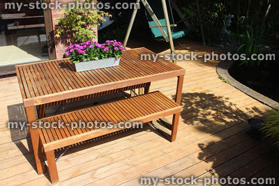 Stock image of slatted wooden garden furniture, table and benches on decking