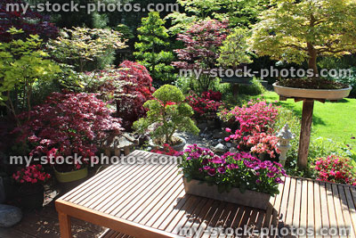 Stock image of slatted wooden garden table, Japanese maples, azaleas, granite lanterns