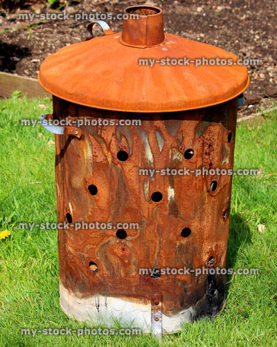 Stock image of rusty garden waste incinerator bin, on lawn grass