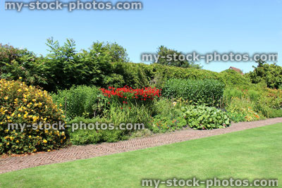 Stock image of red brick path, block paving, paved pathway, herbaceous border, flowers, lawn