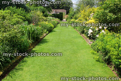 Stock image of ornamental flower garden with lawn pathway, herbaceous plants