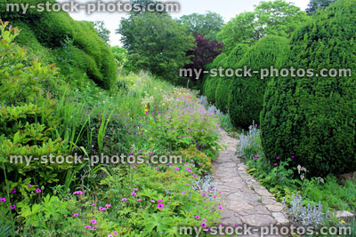 Stock image of informal crazy paving pathway through garden flower border