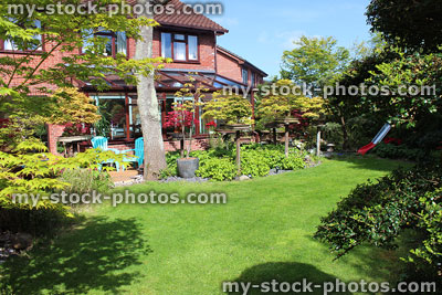 Stock image of house with large back garden, green lawn, conservatory