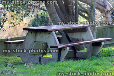 Stock image of concrete picnic table with wooden benches / tabletop