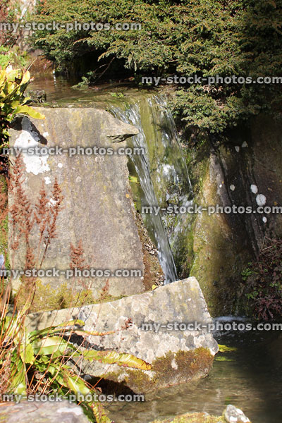 Stock image of vertical waterfall, cascading water feature / stream through rockery garden