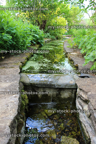 Stock image of small man made stream leading to waterfall / pond, water gardens