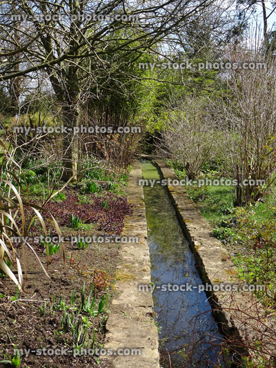 Stock image of stream / rill running through garden with herbaceous flowers