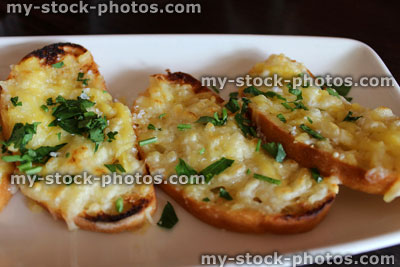 Stock image of garlic bread slices, with melted cheese, fresh herbs