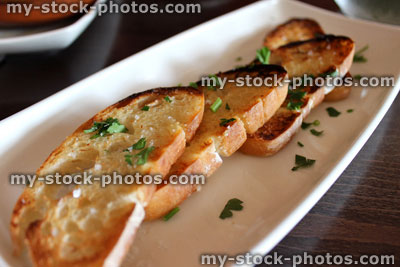 Stock image of garlic bread slices, topped with herbs and toasted