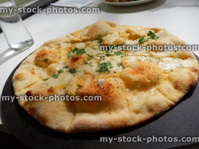 Stock image of garlic bread pizza topped with mozzeralla cheese, herbs