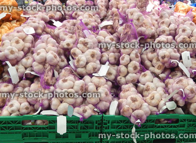 Stock image of strings of garlic cloves / bulbs, net bags, crates, French supermarket