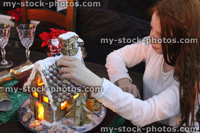 Stock image of girl decorating gingerbread house with sweets at Christmas
