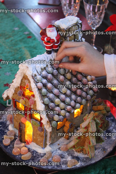 Stock image of Christmas gingerbread house being decorated with sweets / Santa