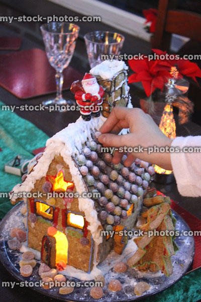 Stock image of child's hand decorating gingerbread house with crystalised sweets