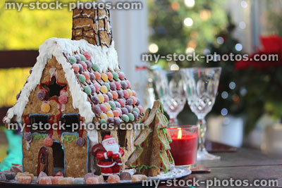 Stock image of gingerbread house on Christmas table, with crystal wine glasses