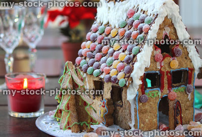 Stock image of gingerbread house with sweets, icing, red candle, cut crystal wine glasses