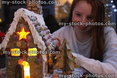 Stock image of girl looking at iced gingerbread house lit up