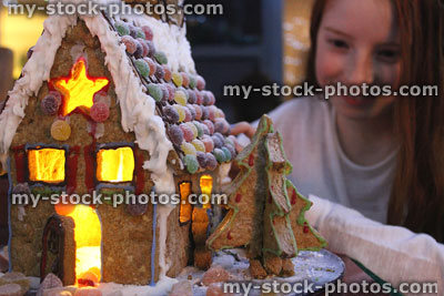Stock image of girl with decorated gingerbread house, lit up at night