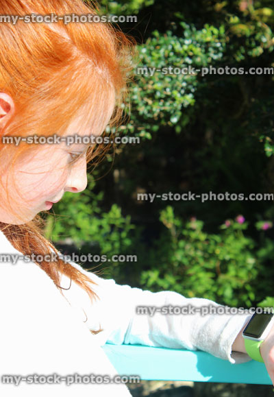 Stock image of girl sitting and looking at smart watch screen