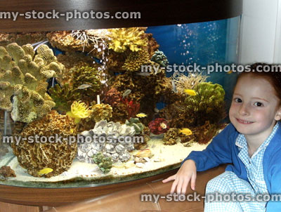 image of girl next to bowed tropical fish tank / aquarium