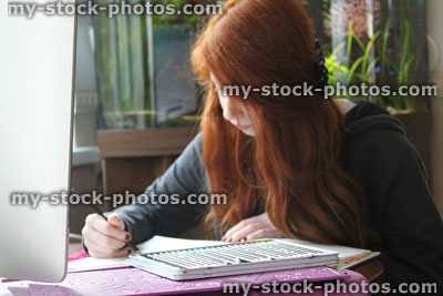 Stock image of girl sitting at table colouring in, art homework
