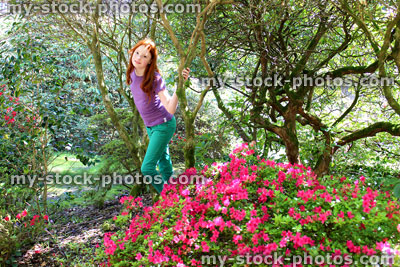 Stock image of girl playing in woodland garden with trees, shrubs and rhododendrons