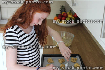 Stock image of young girl baking in kitchen, spooning biscuit mixture