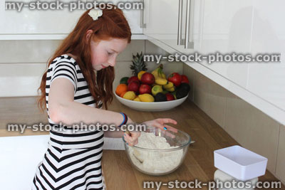 Stock image of young girl baking in kitchen, making biscuits / cookies