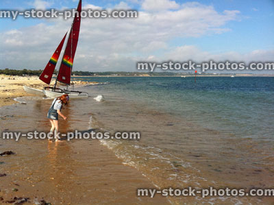 Stock image of red head girl stood on beach near a boat