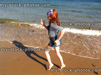 Stock image of red haired girl playing on a beach