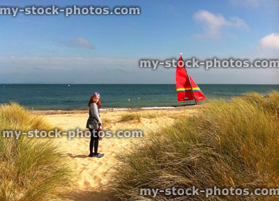 Stock image of girl walking through sand dunes towards a boat
