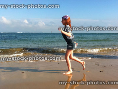 Stock image of red haired girl playing on a beach