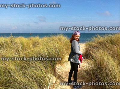 Stock image of girl walking through sand dunes towards the sea