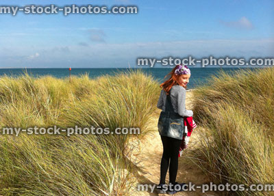 Stock image of girl walking through sand dunes towards the sea