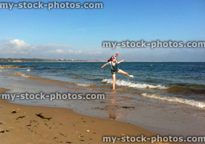 Stock image of red haired girl kicking water on a beach