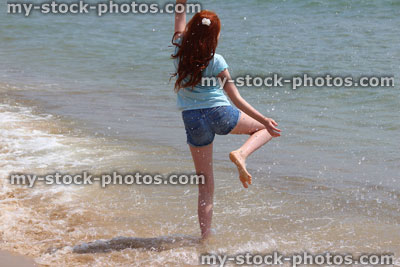 Stock image of girl on beach, playing, splashing, padding in sea