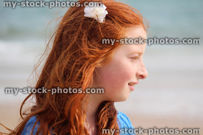 Stock image of girl standing on beach by sea, seaside summer holiday, flower in hair