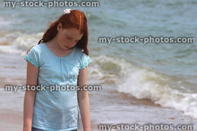 Stock image of girl standing on beach by sea, seaside summer holiday, looking down