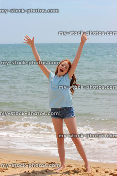 Stock image of girl stretching arms / reaching upwards on seaside beach
