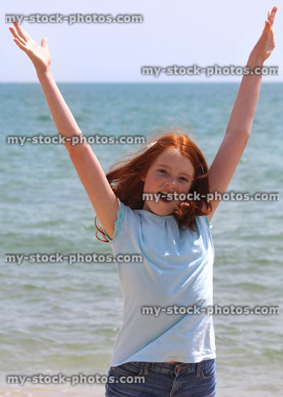 Stock image of girl stretching arms / reaching upwards on seaside beach