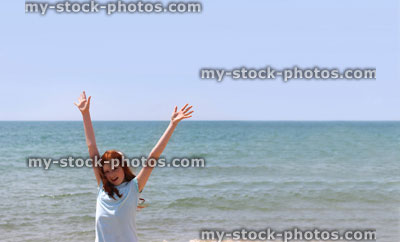 Stock image of girl stretching arms / reaching hands upwards, seaside beach