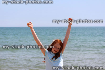 Stock image of girl stretching arms / reaching hands upwards, seaside beach