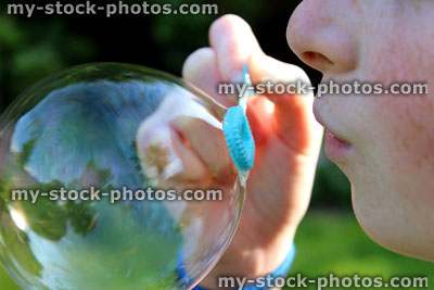 Stock image of girl blowing bubbles in garden sunshine, big bubble