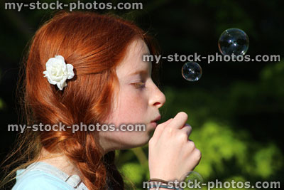 Stock image of girl blowing bubbles in garden sunshine, small bubbles