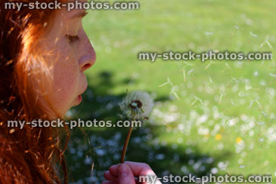 Stock image of pretty girl blowing seeds from a ripe dandelion