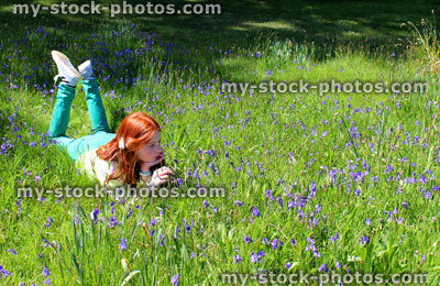 Stock image of girl with long hair lying in woodland bluebells, dappled shade